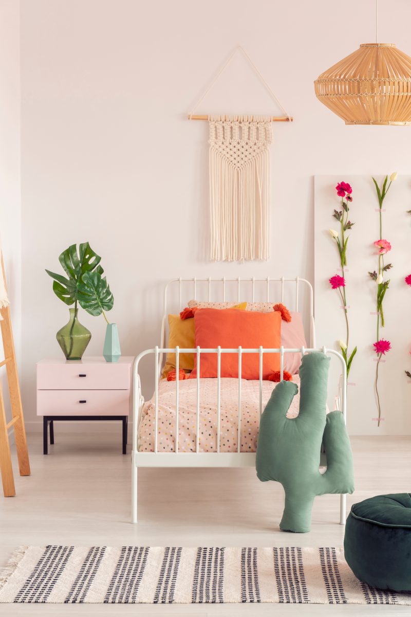 cozy girl's bedroom with flower board and single metal bed